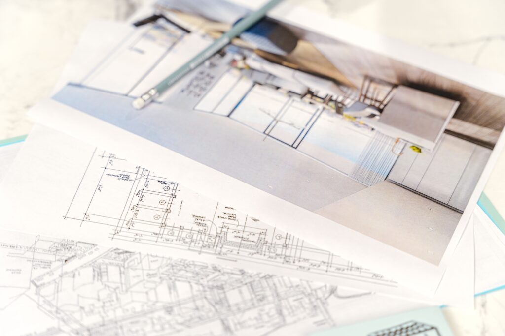 Pièces détachées introuvables ? La France impose les plans 3D aux fabricants Close-up of architectural blueprints and 3D design on paper with pencil on a desk.