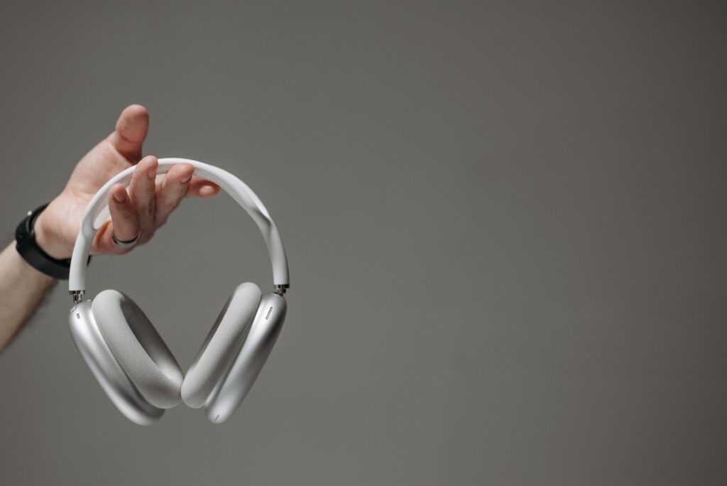 AirPods Max 2 sous les 500 € : le casque premium Apple s’offre une première remise White wireless headphones held by a hand against a neutral gray background.