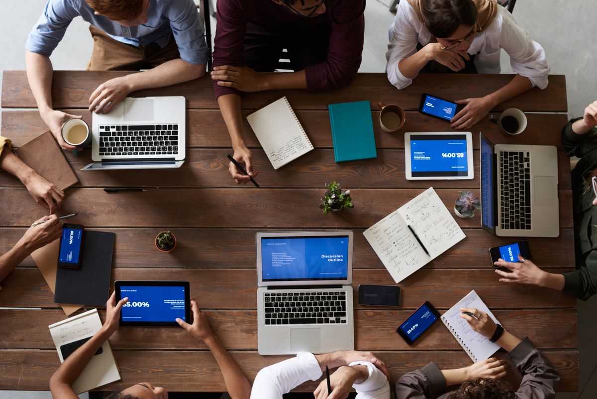 Équipe collaborative en réunion autour d'un bureau avec laptops et documents