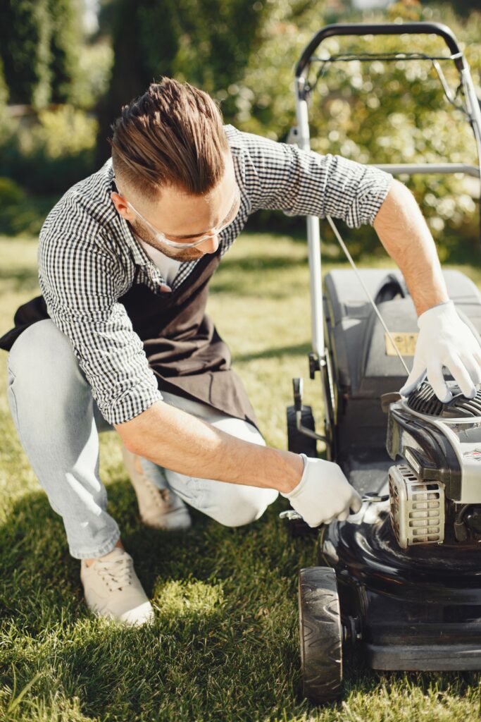 Test Eufy C15 : le robot-tondeuse qui cartographie votre jardin sans fil périphérique Man in a garden repairing lawn mower on sunny day, ideal for gardening and maintenance themes.