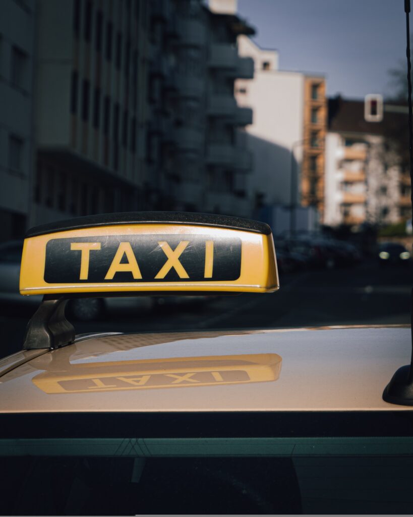 Taxi pour déplacement professionnel à Lille : conseil pratiques et fiabilité Close-up of a taxi sign on a car roof with an urban city background.